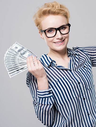 a smiling woman with short blonde hair and glasses, wearing a striped shirt, holding a fan of dollar bills in her hand against a gray background, representing 