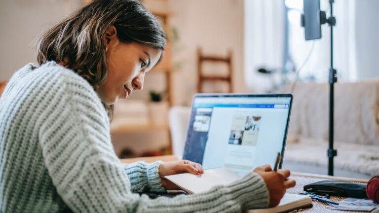 A woman creating cornerstone articles that Google loves while writing in a book.