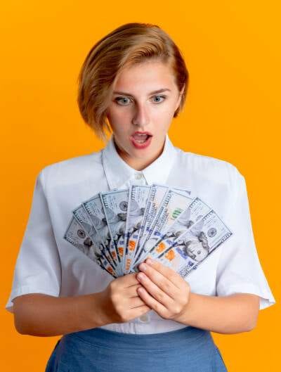 a woman holding a fan of money earned through her best passive income ideas.