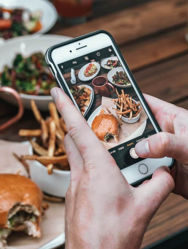 a person holding a phone with food on it, perfect for an instagram post.
