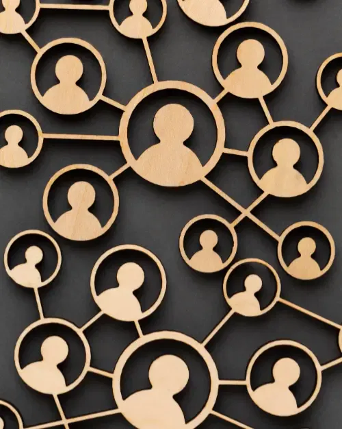 a wooden network of connected human figures on a dark background symbolizes communication strategies and social connections.
