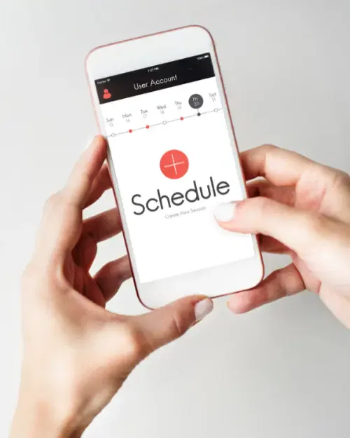 person holding a smartphone with a scheduling app open, displaying a 