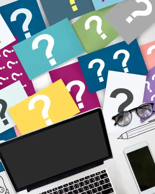 various colorful cards with question marks scattered around a laptop, glasses, a pen, and a mobile phone, resembling the brainstorming process for an article in women's magazines.