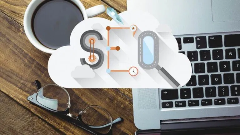 top down view of a desk with a laptop, coffee cup, and glasses, overlaid with graphics of clouds, a dollar sign, and magnifying glasses symbolizing cloud computing and profitable financial analysis.