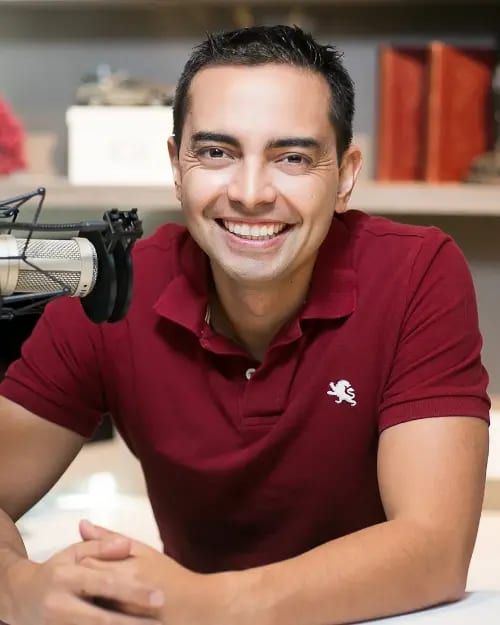 Pat Flynn smiling, seated at a desk in a red polo shirt, ready to share his insights and inspire others through their journey.