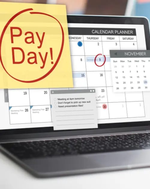 laptop screen showing a calendar with a sticky note marked "pay day!" on the 9th. a small november calendar is displayed beside it. sticky notes about mastering strategies for continuity programs and meeting reminders are on the screen.